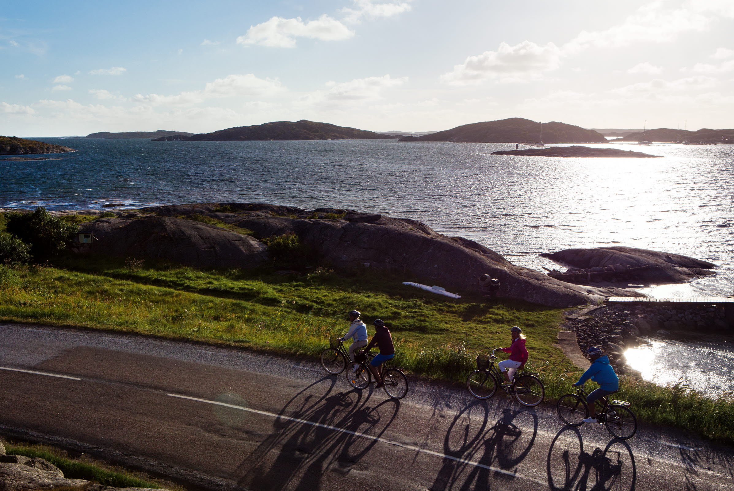a group of people cycling along the sea on the west coast of Sweden