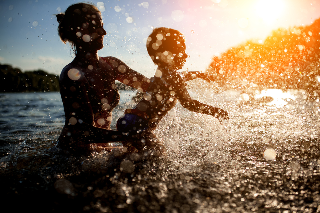 female with child bathe in lake or river and making water drops;